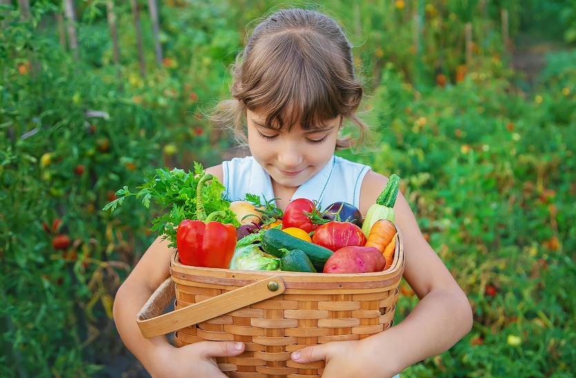 Bimba con cesto di verdure